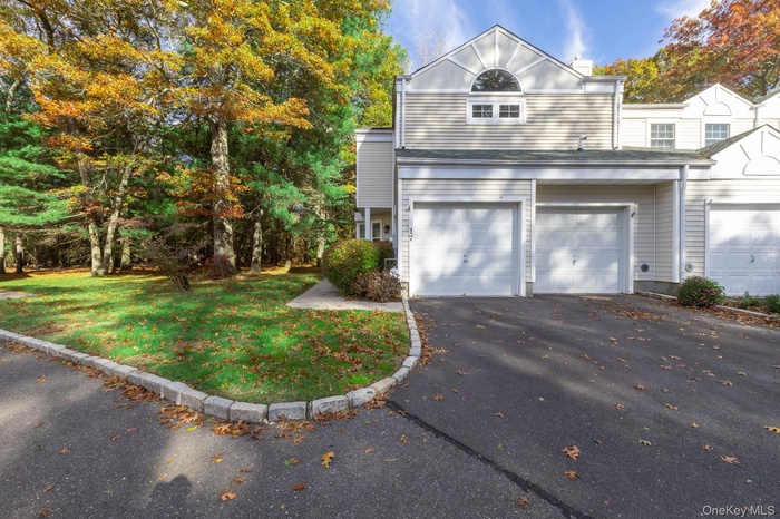 Traditional-style house featuring driveway, an attached garage, and a front lawn
