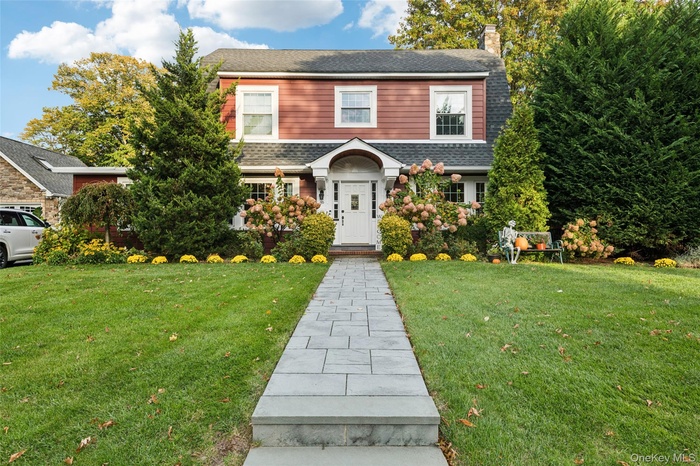 View of front of house featuring a front yard, a chimney, and a shingled roof