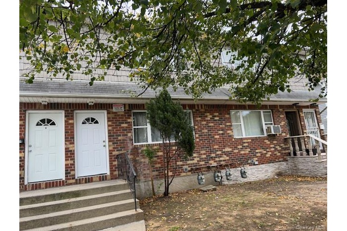 View of front of home with a shingled roof and brick siding