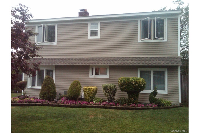 View of front of property with a front yard, entry steps, and a chimney