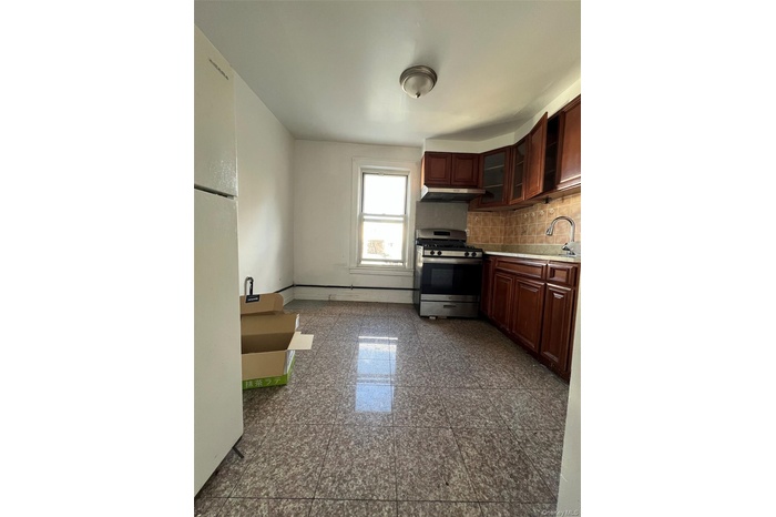 Kitchen featuring gas range, light countertops, glass insert cabinets, freestanding refrigerator, and tasteful backsplash