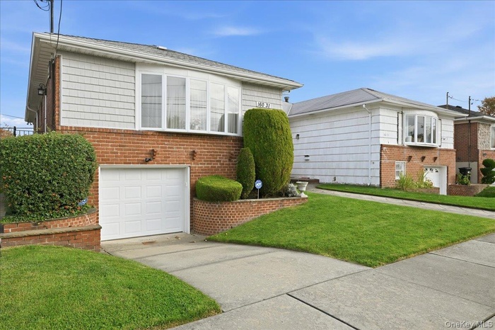View of front facade featuring a front lawn, brick siding, a garage, and concrete driveway