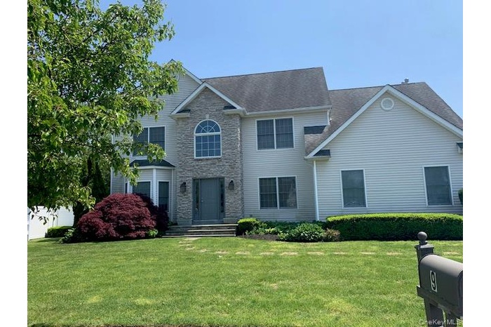 Colonial-style house with a front yard and stone siding