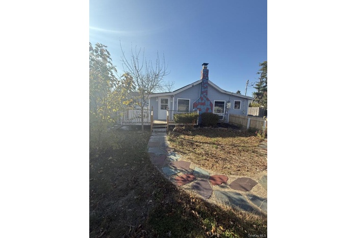 Rear view of house featuring a chimney and a deck