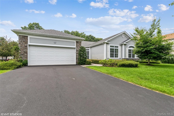 Ranch-style home featuring stone siding, driveway, a front lawn, and a garage