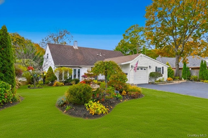 View of front of house featuring a chimney, a front lawn, an attached garage, and asphalt driveway