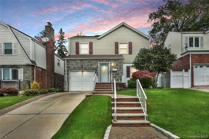 View of front of property featuring concrete driveway, stone siding, and an attached garage
