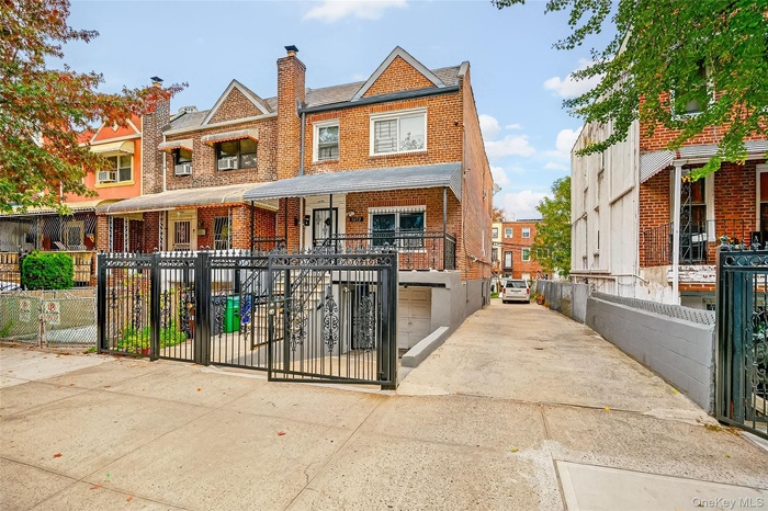 View of front of house with a fenced front yard, concrete driveway, brick siding, an attached garage, and a gate
