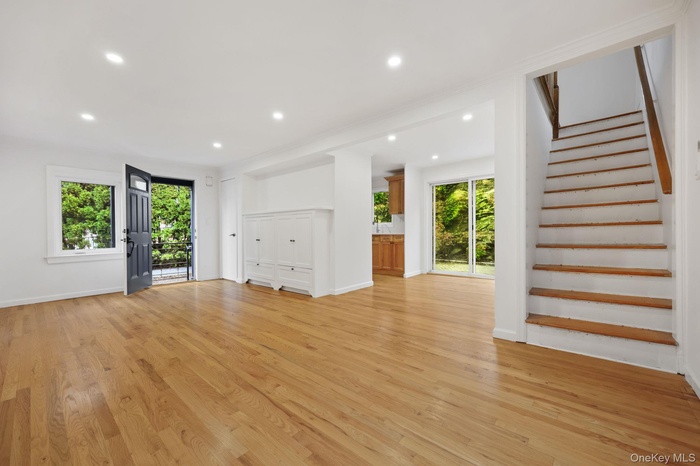 Unfurnished living room with light wood-style flooring, recessed lighting, and stairway