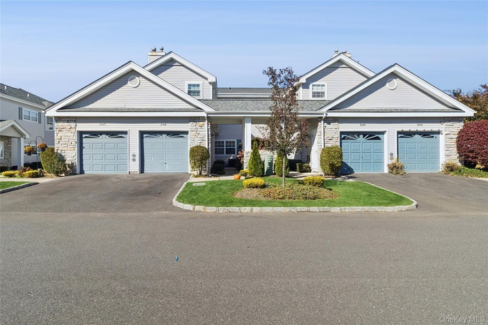 View of front of house featuring asphalt driveway, a chimney, stone siding, and an attached garage
