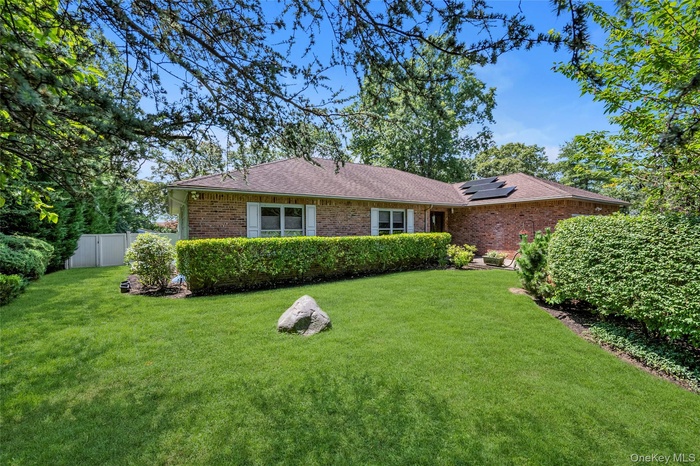 Ranch-style home featuring solar panels, brick siding, and a shingled roof