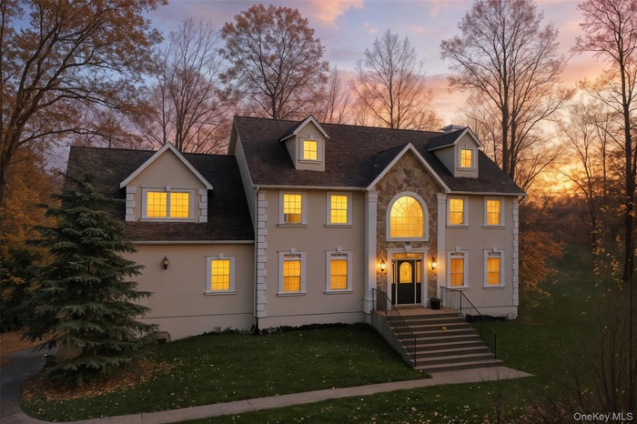 View of front facade with stone siding, a lawn, and a shingled roof