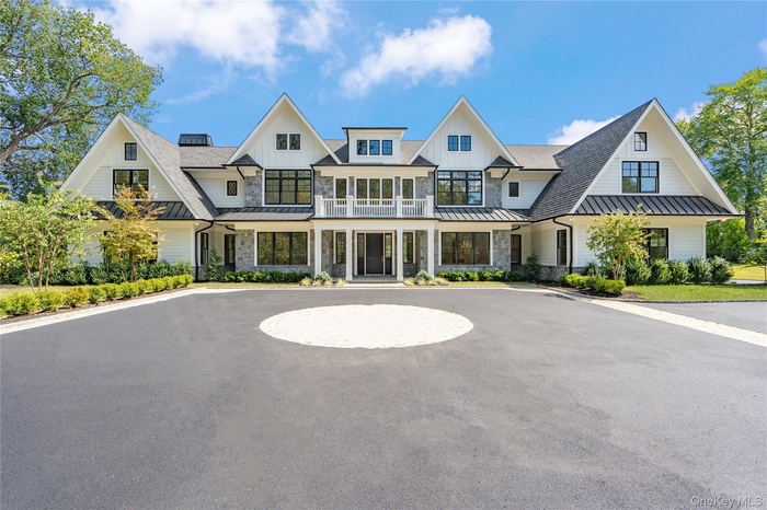 Modern farmhouse featuring a standing seam roof, a metal roof, board and batten siding, and a balcony