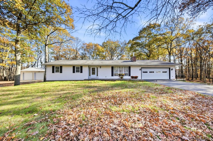 Ranch-style house with a front lawn, a chimney, driveway, and a garage
