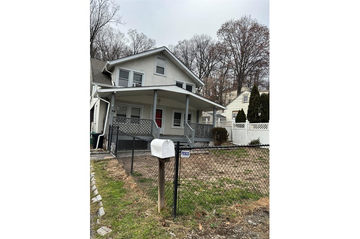 View of front of home featuring a fenced front yard, a gate, covered porch, and stucco siding