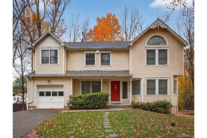 Traditional-style house with driveway, a garage, a front yard, and a porch