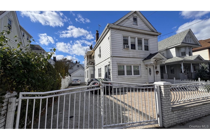 View of front of home with a fenced front yard, a porch, a gate, and a chimney