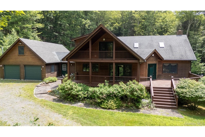Chalet / cabin featuring covered porch, a garage, stairway, and a shingled roof