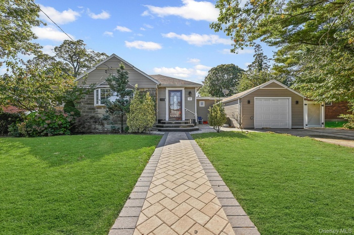View of front of house with an outbuilding, a front yard, roof with shingles, and asphalt driveway