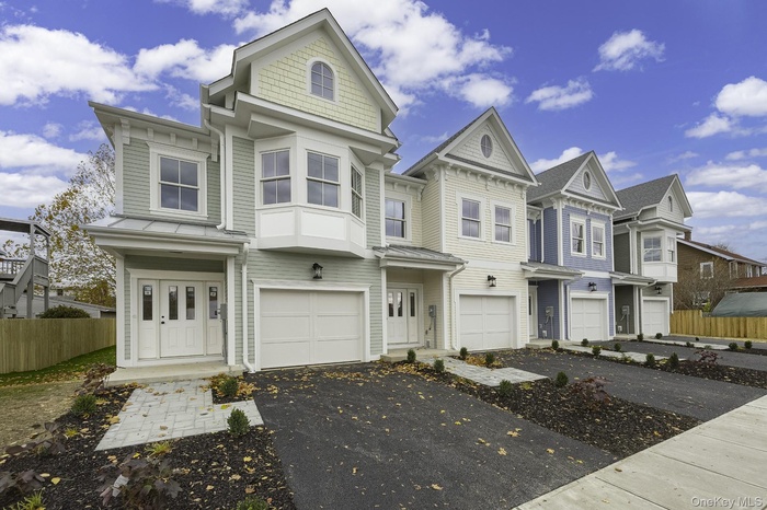 Victorian-style house with a standing seam roof, a metal roof, driveway, a residential view, and a garage
