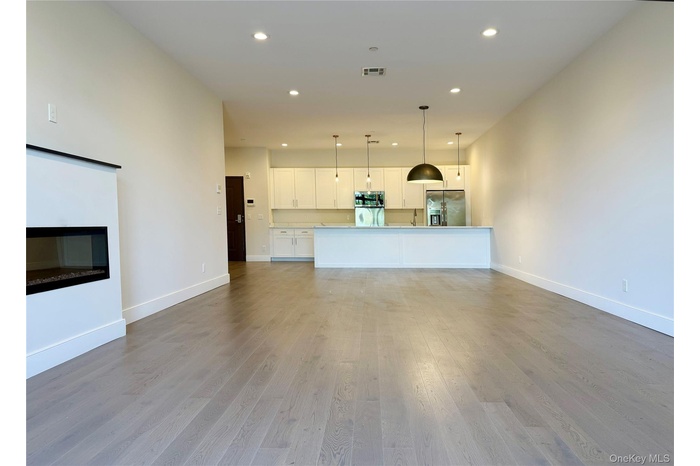 Unfurnished living room featuring recessed lighting, light wood-style floors, and a glass covered fireplace