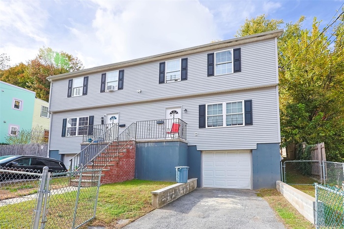 Colonial home featuring a gate, a garage, a fenced front yard, stairs, and driveway
