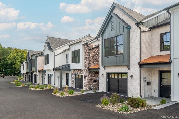 View of front of property featuring board and batten siding, a residential view, an attached garage, and a shingled roof