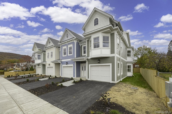 Victorian-style house with an attached garage, a residential view, and asphalt driveway