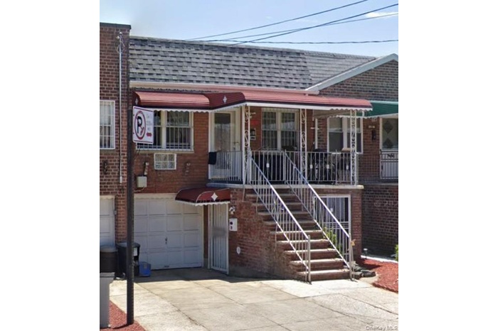View of front of house with a shingled roof, brick siding, driveway, and stairway