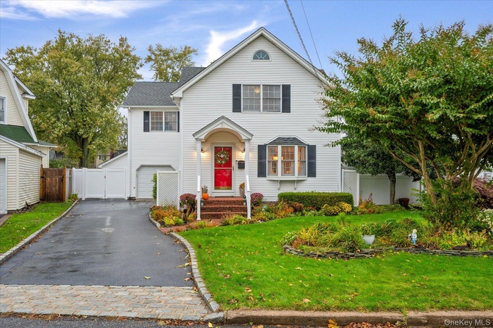 Traditional home with a gate, asphalt driveway, and an attached garage