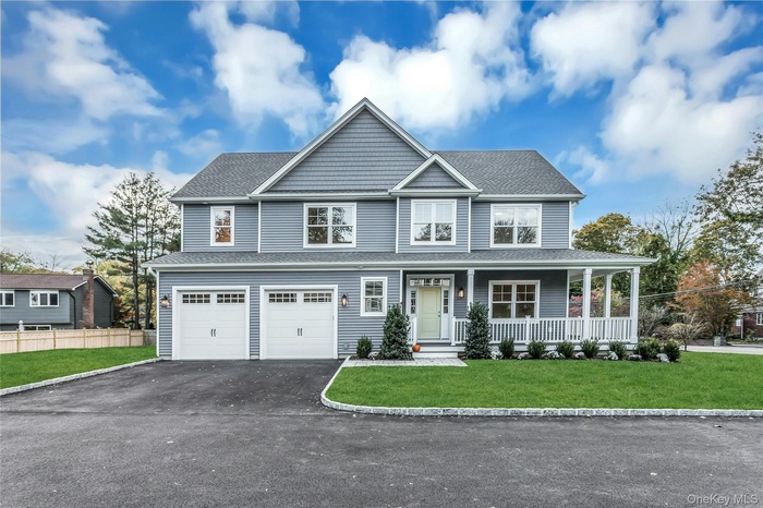 View of front facade with driveway, a garage, covered porch, and a shingled roof