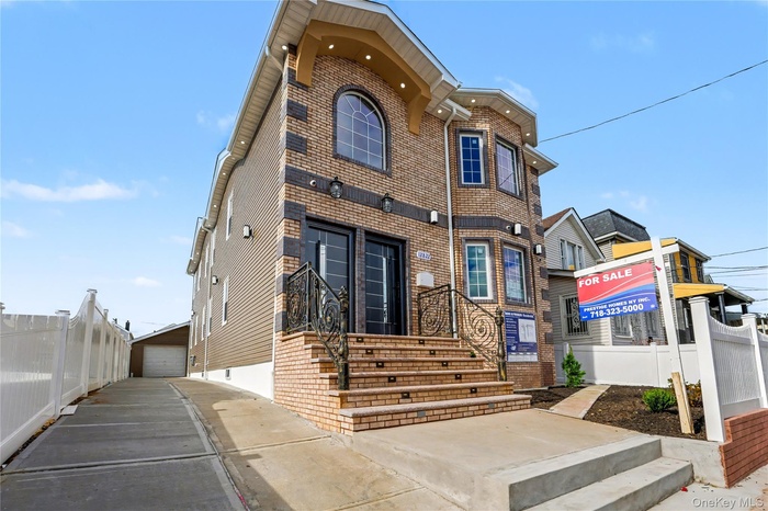 View of front of property with brick siding, a garage, and an outdoor structure