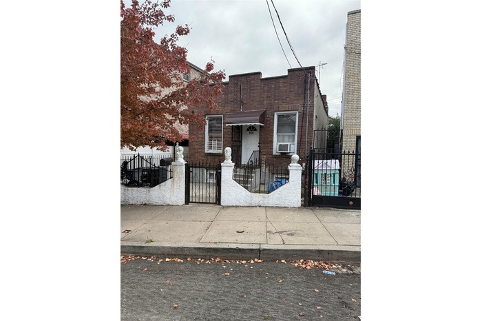 View of front facade with brick siding, a fenced front yard, and a gate