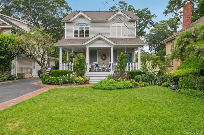 View of front of property featuring covered porch, roof with shingles, and a front lawn