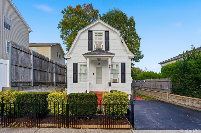 Dutch colonial featuring a gambrel roof and a fenced front yard