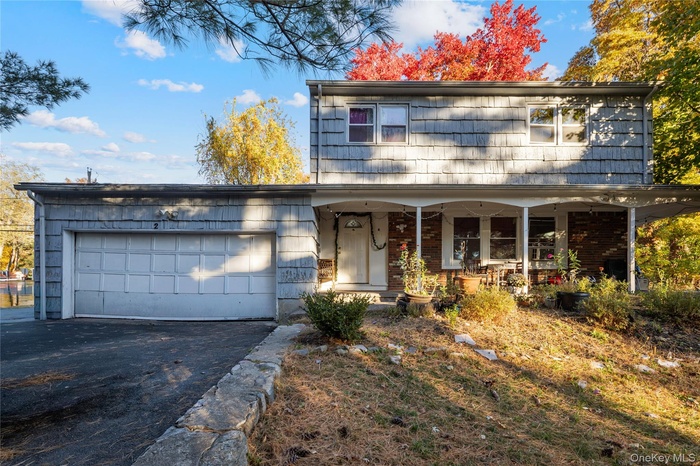 View of front of property featuring asphalt driveway, a garage, and a porch