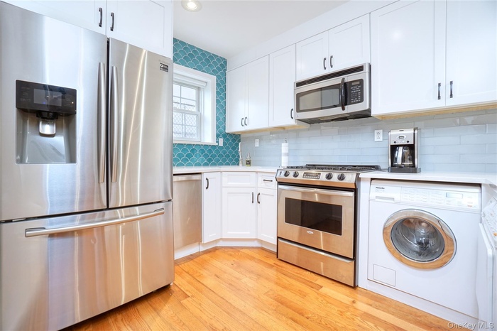Kitchen with stainless steel appliances, washer / clothes dryer, white cabinetry, decorative backsplash, and recessed lighting