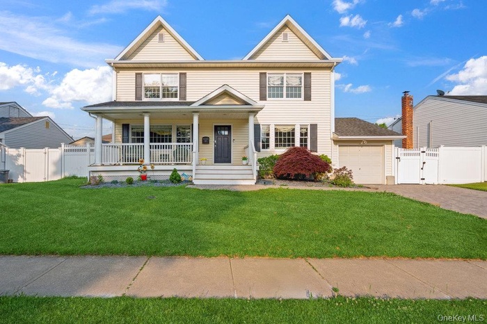 View of front of home with covered porch, a gate, and driveway