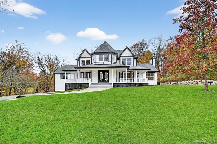 View of front of house with a porch, a front lawn, and roof with shingles