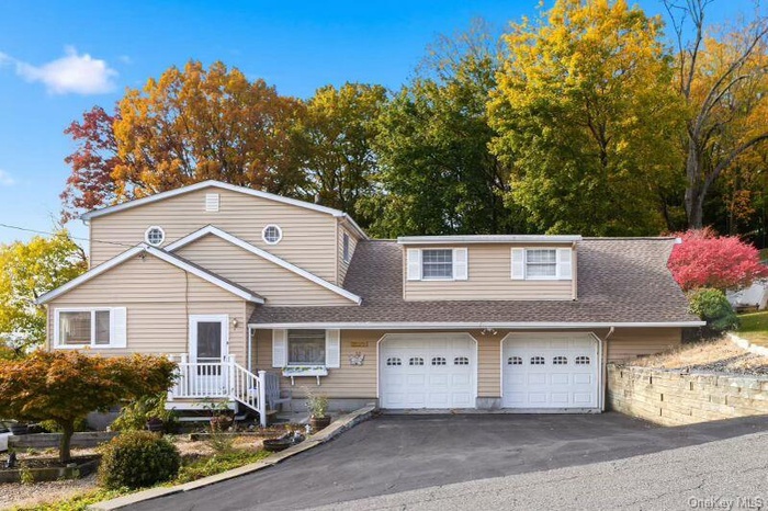 Traditional home featuring roof with shingles, driveway, and a garage