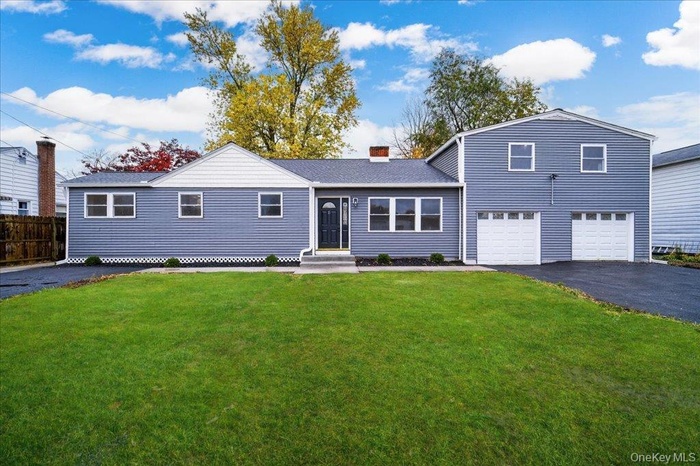View of front of house with a garage, driveway, and a chimney