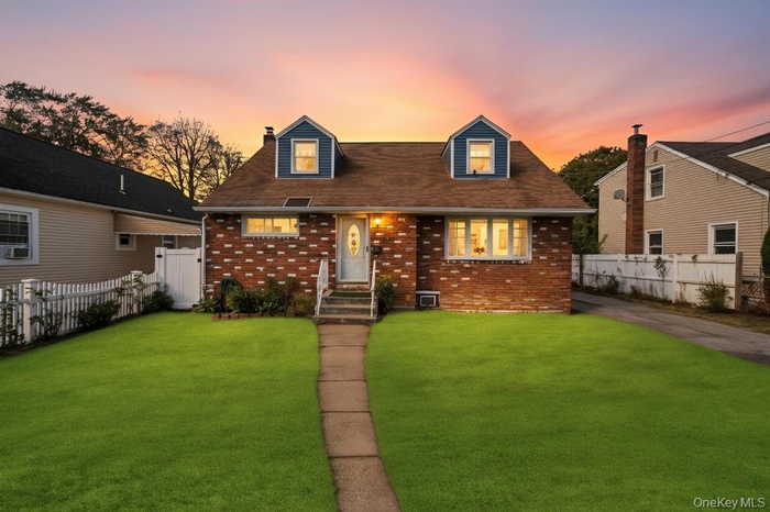 Cape cod home featuring brick siding