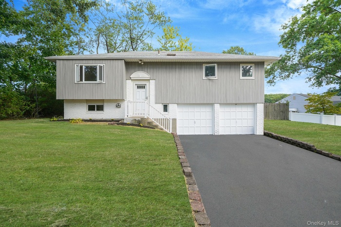 Bi-level home with asphalt driveway, an attached garage, and brick siding