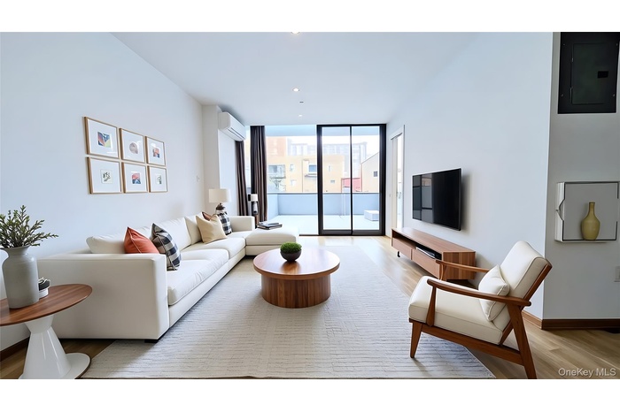 Living area with electric panel, expansive windows, light wood-type flooring, and a wall mounted air conditioner