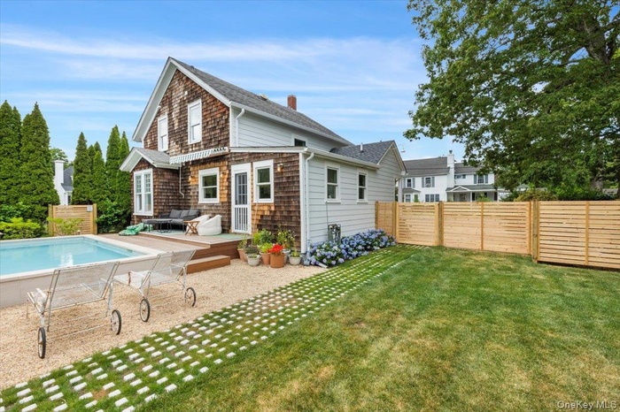 Rear view of property featuring a wooden deck, a fenced backyard, roof with shingles, and a chimney
