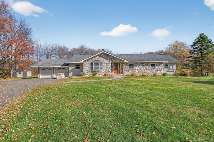 Ranch-style home with asphalt driveway, a front yard, stone siding, and a garage