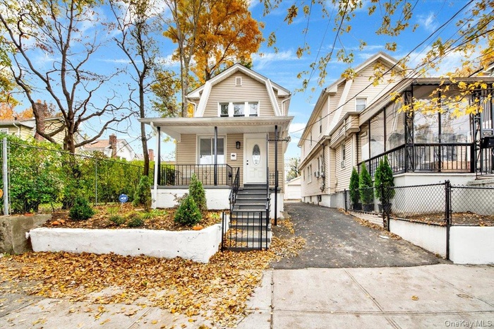 View of front of house with a fenced front yard, covered porch, and driveway