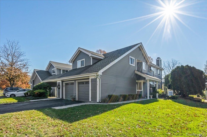 View of side of property featuring a yard, asphalt driveway, a shingled roof, and a garage