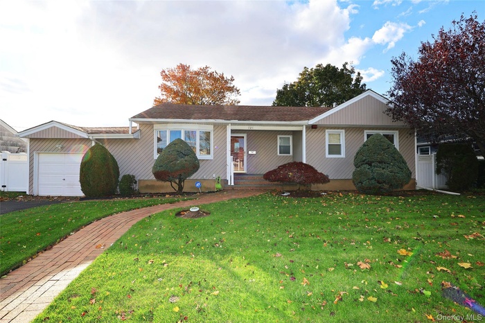 Ranch-style home with a front yard, an attached garage, and covered porch