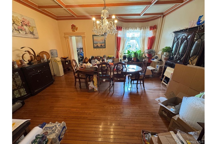 Dining space featuring dark wood finished floors, coffered ceiling, beamed ceiling, and a chandelier